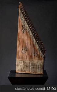 ancient Asian stringed musical instrument on black background with backlight. the similarity of the harp and psaltery. national musical instrument of Asia