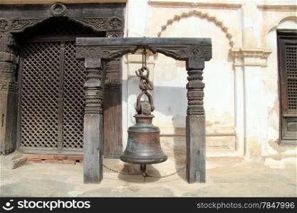 Ancient bronze bell near wooden door of palace in Bhaktapur, Nepal
