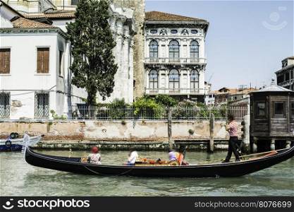Ancient buildings and boats in the channel in Venice. Gondolier