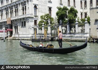 Ancient buildings and boats in the channel in Venice. Gondolier