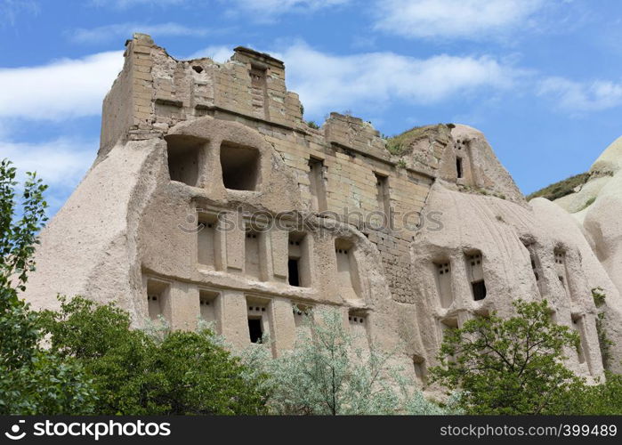 Ancient caves in a mountain landscape between the valleys in Cappadocia against a bright blue spring sky, central Turkey. Mountain Honey and Red valleys in Cappadocia