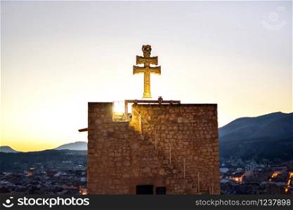 Ancient christian cross against the town of Caravaca, Spain.. Ancient christian cross against townscape of Caravaca, Spain.