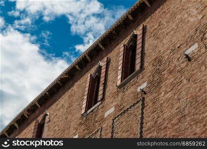 Ancient Facade with Visible Brick Work along Typical Water Canal in Venice, Italy