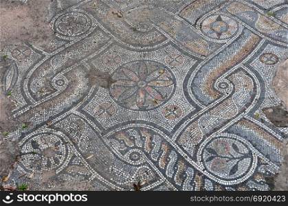 Ancient floor roman mosaic geometric shapes motif abstract pattern and fallen leaves. Athens, Greece.