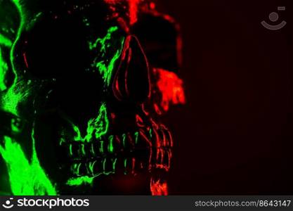 Ancient human skull head close-up. Neon green and red light. Spooky and sinister. Glamour, disco, halloween concept. Ancient human skull head close-up. Neon green and red light. Spooky and sinister. Glamour, disco, halloween concept.