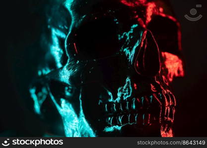 Ancient human skull head close-up. Neon turquoise and red light. Spooky and sinister. Glamour, disco, halloween concept. Ancient human skull head close-up. Neon turquoise and red light. Spooky and sinister. Glamour, disco, halloween concept.
