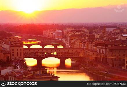 Ancient Italian bridge across Arno river in bright yellow sunset light, Florence, Europe, famous historical landmark, travel and tourism concept