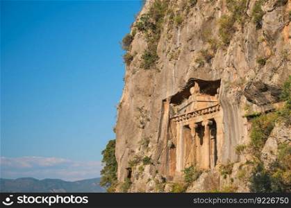 Ancient Lycian rock tombs on the rocks above the city of Fethiye on the Aegean coast of Turkey, Lycian tombs at sunset in spring, the rock-cut tombs of Amyntas rise above the city, travel and vacation