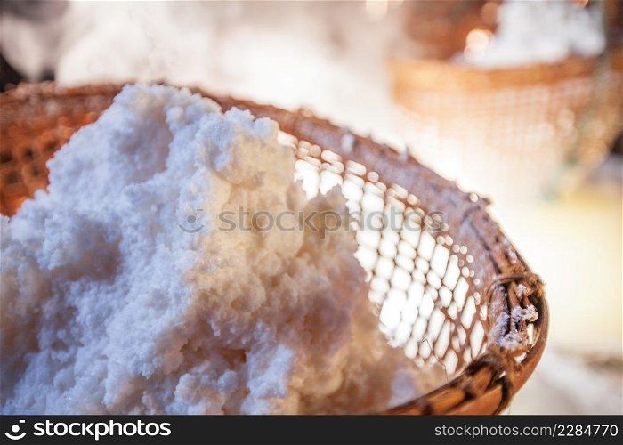 Ancient method of boiling brine into pure salt in Bo Kluea, Nan, Thailand. Beautiful smoke, sunlight shines down around ancient salt pits and bamboo basket. Traditional, culture rock salt. History of salt.