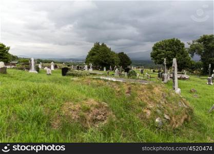 ancient monument and burial concept - old headstones and ruins on celtic cemetery graveyard in ireland. old celtic cemetery graveyard in ireland