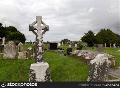 ancient monument and burial concept - old headstones and ruins on celtic cemetery graveyard in ireland. old celtic cemetery graveyard in ireland