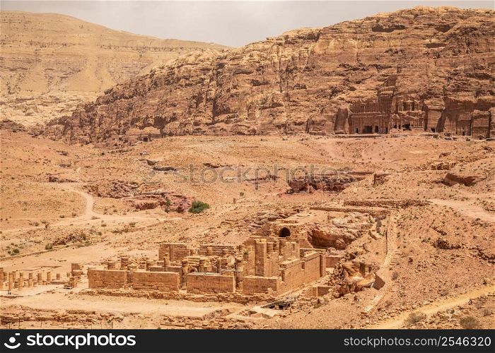 Ancient Nabataean Royal tombs in the background and ruins of grand temple in the foreground, Petra, Jordan