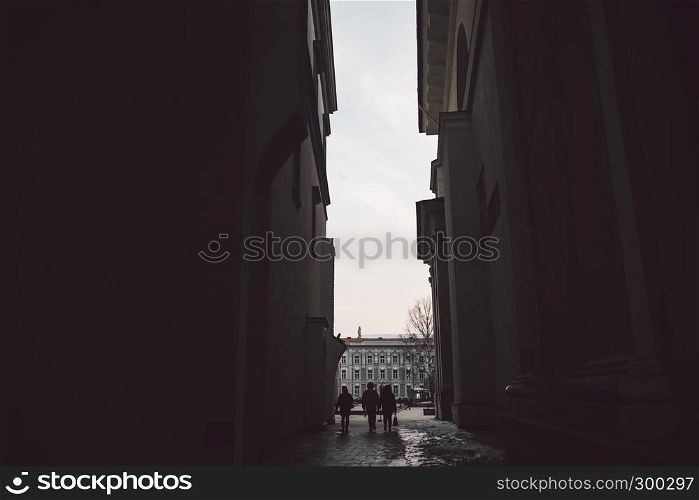 Ancient narrow Vilnius street with dark people silhoettes