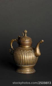 ancient oriental metal teapot on dark background. antique bronze tableware. ancient metal utensils