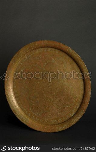 ancient oriental metal tray on dark background. antique bronze tableware. tray with engraving