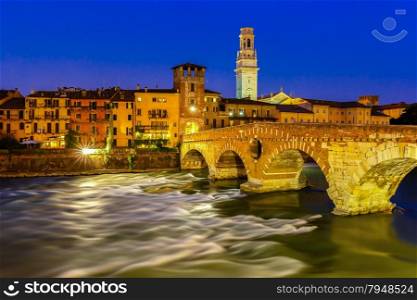 Ancient Roman bridge Ponte Pietra and the River Adige at night illumination, Duomo tower in background, Verona, Italy