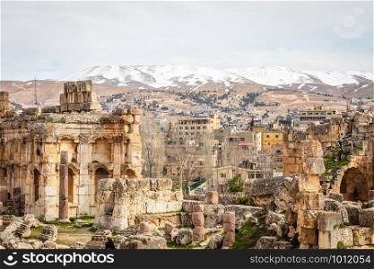 Ancient ruins of Grand Court of Jupiter temple, with modern lebanese houses in the background, Beqaa Valley, Baalbeck, Lebanon