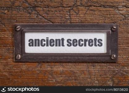 ancient secrets tag - file cabinet label, bronze holder against grunge and scratched wood -internet publishing concept