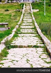 Ancient staircase made of natural stone with green grass