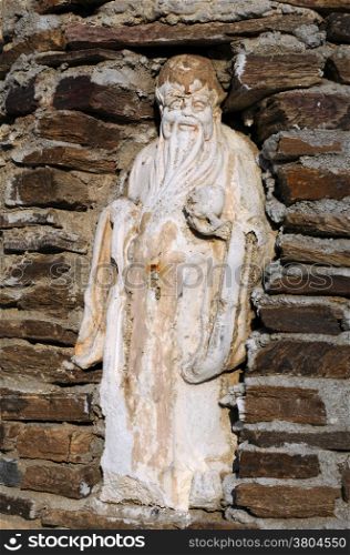 Ancient statue of an old man in the niche in the brick wall in Turkey