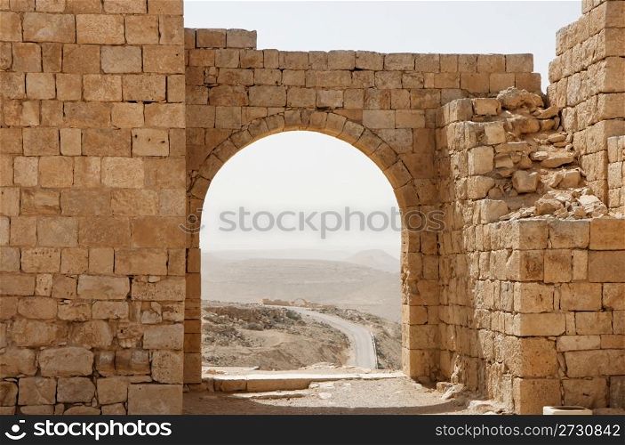 Ancient stone arch and wall with desert view during sandstorm