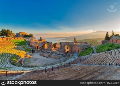 Ancient theatre of Taormina Siciliy Italy with Etna erupting volcano at sunset