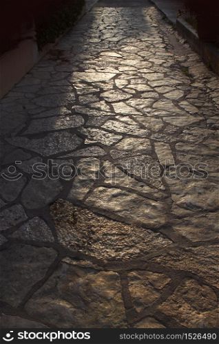 Ancient tiled stone pathway in warm evening backlight. Old tiled pathway