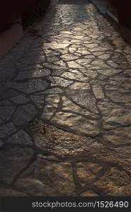 Ancient tiled stone pathway in warm evening backlight. Old tiled pathway