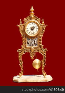 ancient vintage brass pendulum clock isolated on red