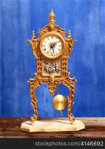 ancient vintage golden brass pendulum clock in blue grunge background