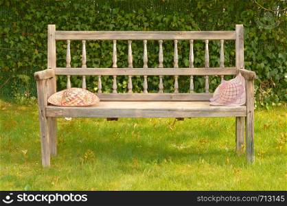 Ancient wooden bench in a garden with two straw hats on a sunny day. Ancient wooden bench in a garden with two straw hats