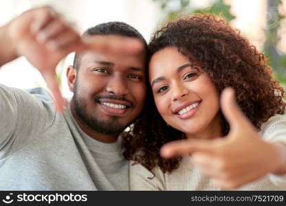 and people concept - happy african american couple making selfie or viewfinder gesture at home. happy couple making selfie gesture at home