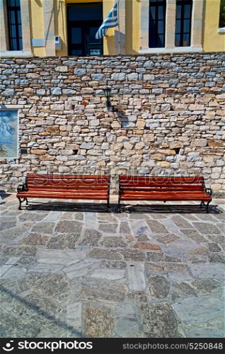 and stone pavement in the greece island of paros old bench near a brick antique wall