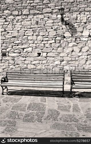 and stone pavement in the greece island of paros old bench near a brick antique wall