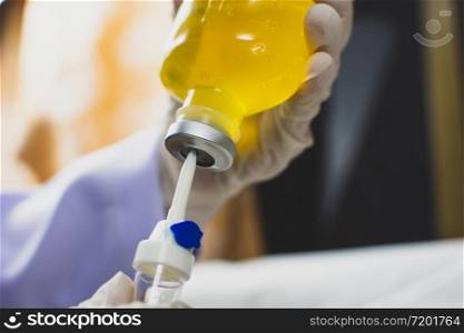 Anesthesiologist Doctors hand inject I.V. drip set into normal saline solution (NSS) bottle,Coronavirus treatment concept,Covid-19.