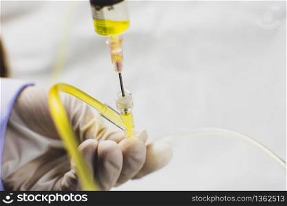 Anesthesiologist Doctors hand inject the medication through a syringe into extension tube of normal saline solution.