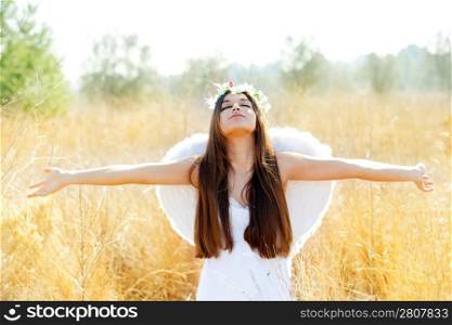 Angel etchnic woman in golden field with feather white wings and flowers crown