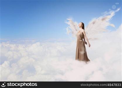 Angel girl flying high. Attractive woman with angel wings on sky background