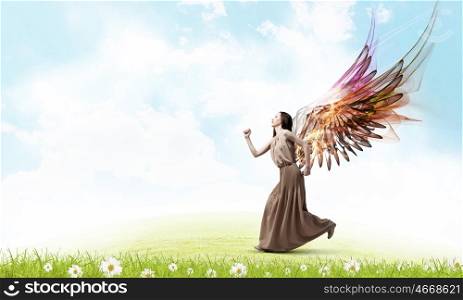 Angel girl in dress. Attractive woman running with angel wings behind back