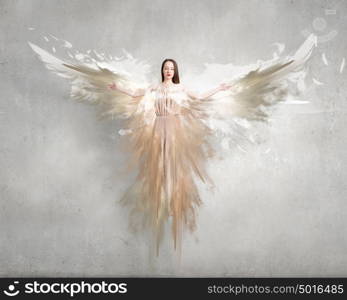 Angel girl in dress. Attractive woman with angel wings on concrete background