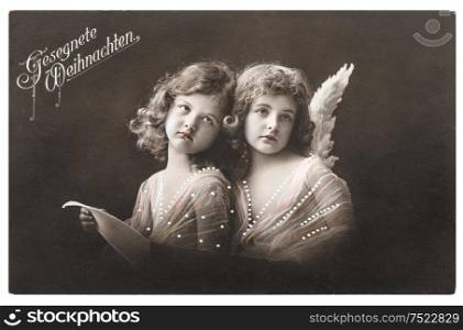 Angel girls with white wings. Christmas greetings card. Vintage picture with original film grain and blur, 1912