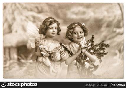 Angel girls with white wings, toys and christmas tree. Vintage picture with original film grain and blur