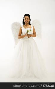 Angelic mid-adult African-American bride holding a bouquet on white background.