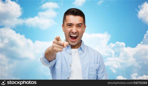 anger, emotions, aggression, gesture and people concept - angry man shouting and pointing finger on you over blue sky and clouds background