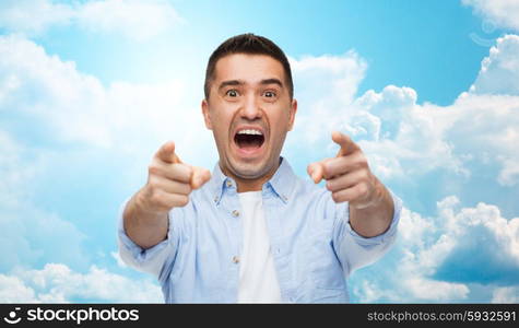 anger, fear, emotions, gesture and people concept - angry or scared man shouting and pointing finger on you over blue sky and clouds background