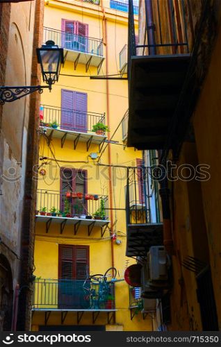 Angle view of narrow side street with colorful yellow house in the end in Palermo, Sicily, Italy