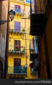 Angle view of narrow side street with colorful yellow house in the end in Palermo, Sicily, Italy
