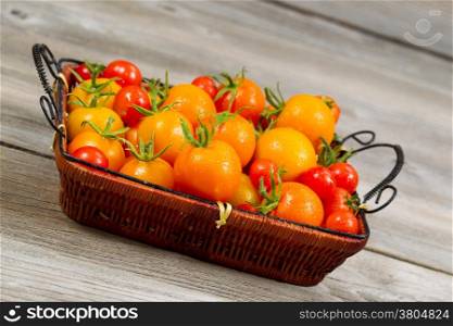 Angled view of garden fresh tomatoes in basket on rustic wooden boards