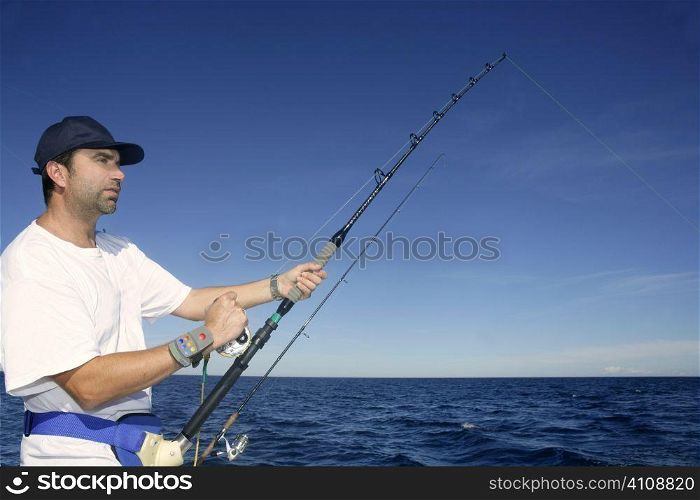 Angler fisherman trolling rod and reel fighting saltwater fish