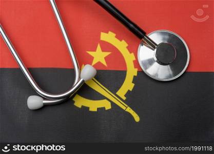 Angola flag and stethoscope. The concept of medicine. Stethoscope on the flag as a background.. Angola flag and stethoscope. The concept of medicine.